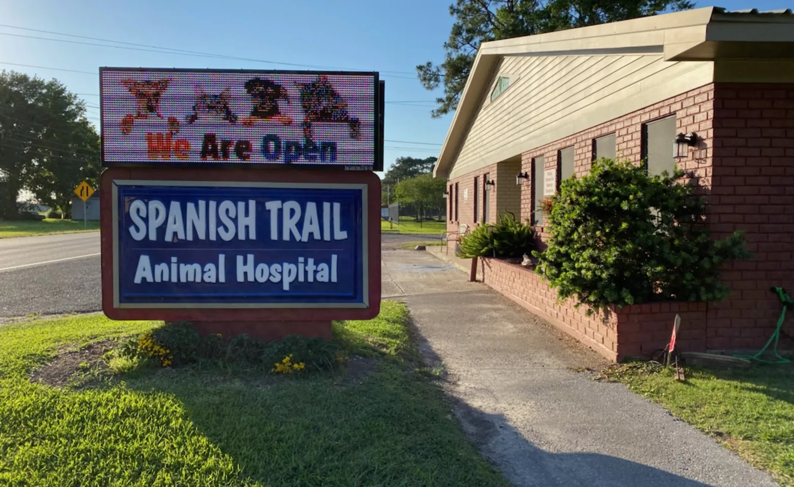Spanish Trail Animal Hospital's front of their building which consist of redbricks and a tan roof with their signage on the right side of the picture